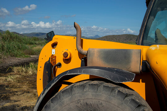 Close Up of Yellow Construction Machine Wheel and Exhaust Outdoo