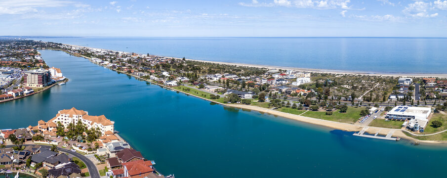 Aerial panoramic view of West Lakes in Adelaide, South Australia, the turquoise lake running parallel to the sandy coastline, surrounded by waterfront luxury houses, affluent residential suburbs.