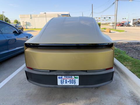 Dallas, Texas, USA - October 15th, 2026: Rear view of gold Tesla Cybercab parked in service center lot with Texas manufacturer license plate