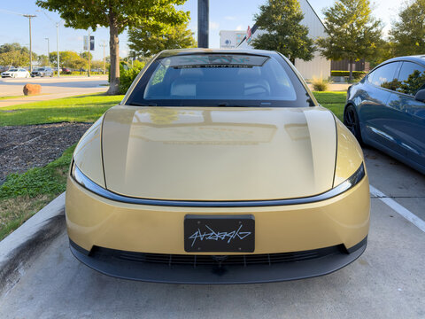 Dallas, Texas, USA - October 15th, 2026: Front view of gold Tesla Cybercab vehicle parked outdoors in service center parking lot front space