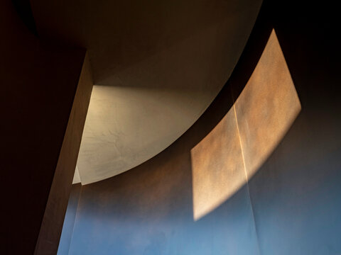 Curved bronzed siding on walls and light patterns of interiors in a single family residence.