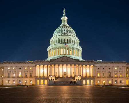 Washington, D.C., USA: The U.S. Capitol Building illuminated at night, with its dome lit against a dark blue sky and the plaza in front empty.