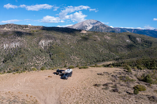Aerial view of two vehicles in dispersed camping site in Colorado backcountry under sunny autumn cloudscape.