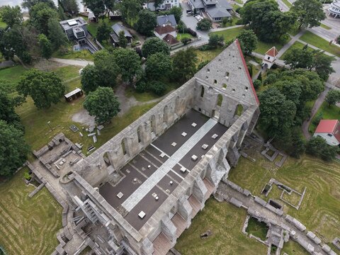 Aerial view of the historic ruins of Pirita Convent, featuring the tall stone gable wall and open-air nave floor, surrounded by green lawns and trees in Tallinn, Harju maakond, Estonia.