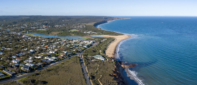 Aerial drone view of the coastal town of Anglesea along the Great Ocean Road in Victoria, Australia, the winding coastal highway, sandstone cliffs, and the Anglesea River estuary merging into the sea