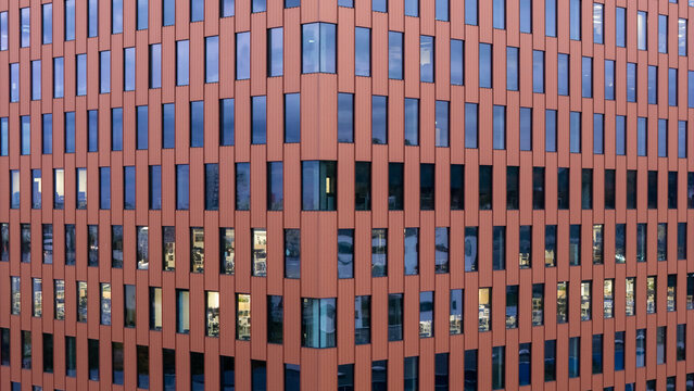 Aerial view of a modern office building facade featuring rhythmic vertical panels and reflective glass windows in Gdansk, Poland.
