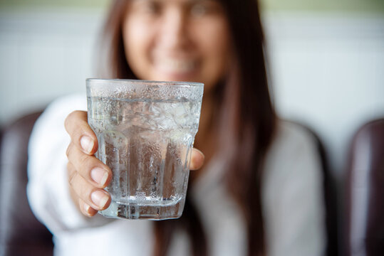 Woman drinking water hands holding cold mineral water cool drinking. Asian women smile laugh look away healthcare home fitness lifestyle. Cheerful Beautiful female drink glass of water smile face