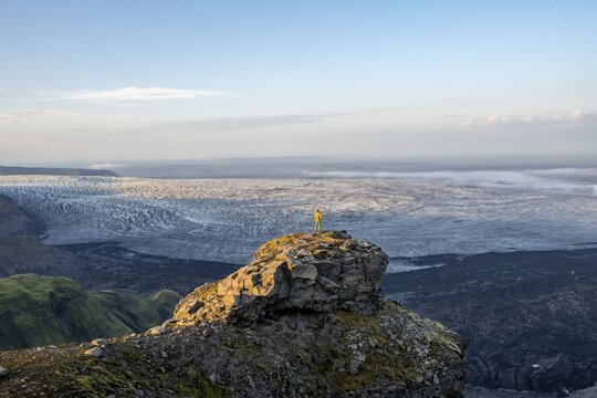 Young man, tourist in front of impressive glacier, in evening light, landscape with mountains and glacier, glacier tongues K&ouml;tluj&ouml;kull, Myrdalsj&ouml;kull glacier Pakgil, Iceland
