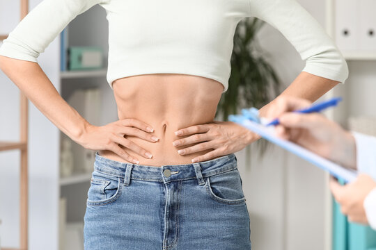 Eating disorder and body image issues, young woman with underweight physique consulting with a doctor in a medical clinic for health assessment