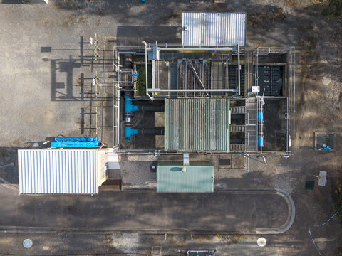 Aerial view of the Brushy Creek Wastewater Treatment Plant featuring industrial tanks, metal roofing, blue piping, and surrounding gravel grounds in Chirnside Park, Victoria, Australia.