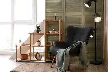 Home comfort and interior design, cozy reading nook with armchair and wooden shelving in a bright living room with natural light and minimalist decor © Pixel-Shot