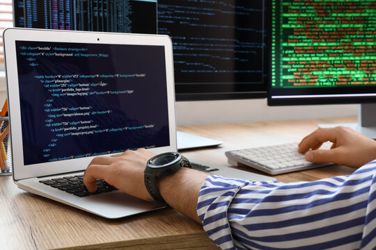 Software development and coding, programmer working on laptop with multiple monitors and web programming language in a modern office workspace