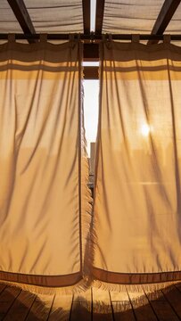 Vertical video: Breeze causing fringed curtains billowing inward on rooftop, filtering warm sun