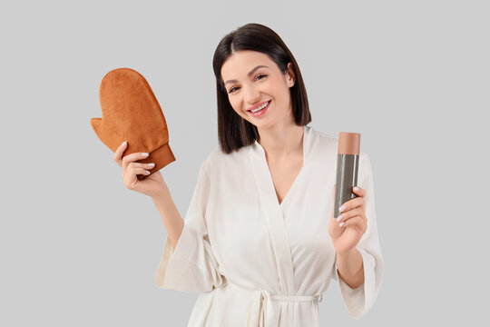 Self tanning routine and skincare, woman in bathrobe holding tanning mitt and spray bottle for sunless tan application on a neutral background