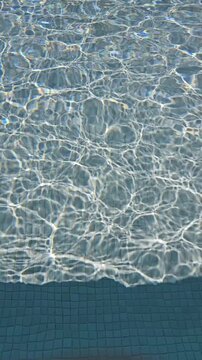 Abstract surface of water pool with sunlight ripple wave patterns vertical video