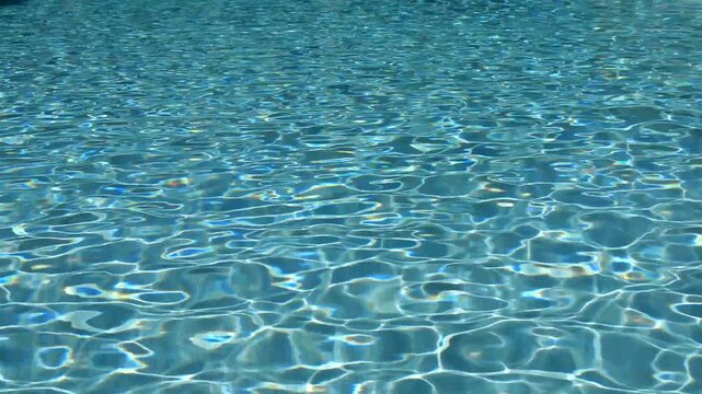Abstract turquoise colored surface of water pool with sunlight ripple wave patterns
