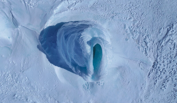 Aerial view of a frozen Tsalka Reservoir with a striking blue ice formation and snow-covered landscape in Tsalka, Kvemo Kartli, Georgia.