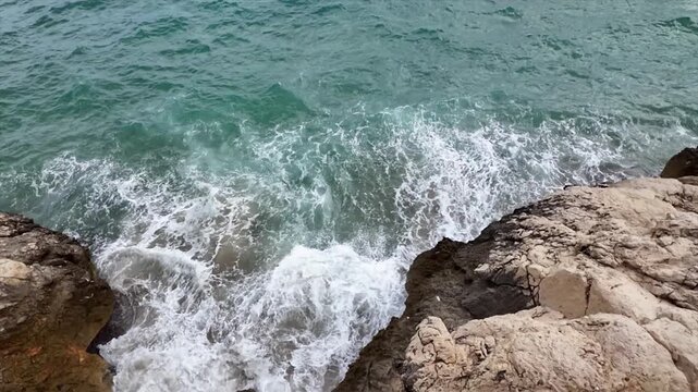 Top-down view of waves breaking over rocks on the Barcelona coast