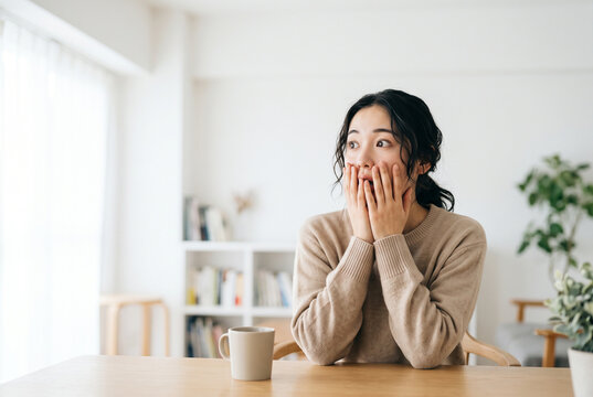 マグカップを持って驚いた表情を見せる女性