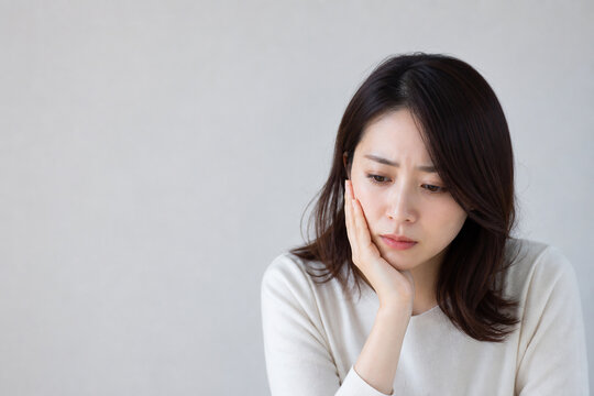 頬に手を当ててうつむく女性