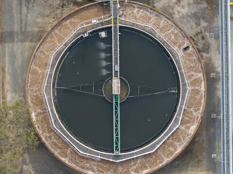 Aerial view of the circular clarifier tank at the Brushy Creek Wastewater Treatment Plant with aerated water and industrial infrastructure in Chirnside Park, Victoria, Australia.