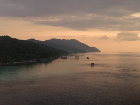 Aerial view of Kri island with overwater bungalows along the lush coastline of Meos Mansar, Southwest Papua, Indonesia.