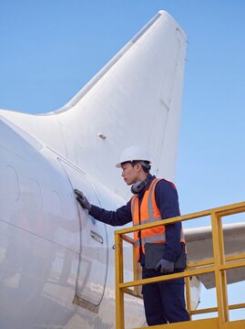 Aircraft technician on a maintenance platform inspecting the fuselage skin for airframe safety checks