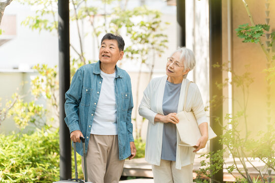 Happy senior couple smiling and setting off on a trip with their suitcases.