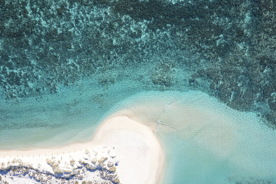 Aerial view of Turquoise Bay showing the white sand beach meeting the vibrant turquoise water and the intricate coral reef patterns in Cape Range National Park, Western Australia, Australia.