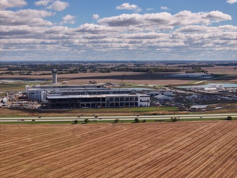 Aerial view of a large industrial construction site featuring steel frameworks, cranes, and surrounding agricultural fields near a highway in Washington Court House, Ohio, United States.