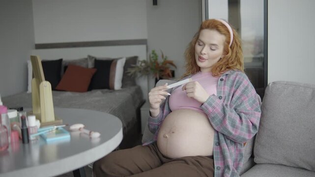 A pregnant woman sits on a sofa in the living room and gives herself a manicure using a Japanese-style nail file.