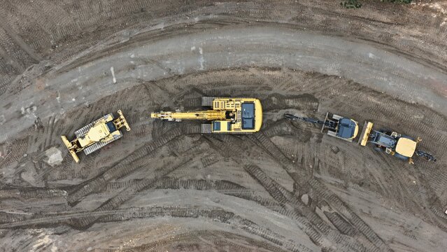 Aerial view of yellow construction machinery including excavators and bulldozers parked on a dirt site with tire tracks in Estes Park, Colorado, United States.