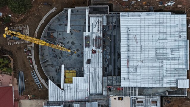 Aerial view of a construction site featuring a yellow crane, metal roofing panels, and building materials in Estes Park, Colorado, United States.