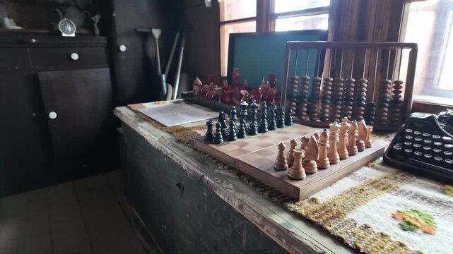 A slow cinematic camera move toward a wooden chessboard set for play in a historic rural house, with an antique abacus and vintage typewriter in the background.