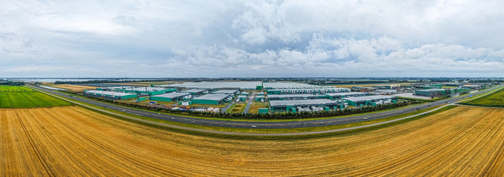 Aerial view of Agriport A7, a large-scale greenhouse complex and logistics hub, surrounded by vast agricultural fields and the A7 motorway in Middenmeer, Noord-Holland, Netherlands.