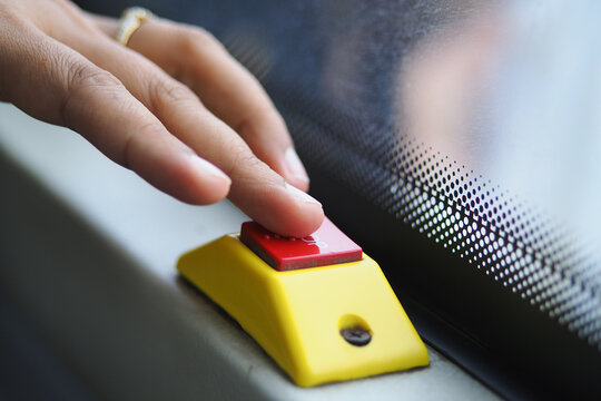 Finger pressing red button on yellow control beside a car windshield