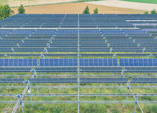 Aerial view of a modern agrivoltaic solar farm with elevated photovoltaic panels allowing crops to grow underneath, combining renewable energy and agriculture in Valence, Auvergne-Rhone-Alpes, France.