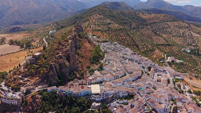 Aerial view along the spine of Zahara de la Sierra with olive groves covering the slopes, Spain.