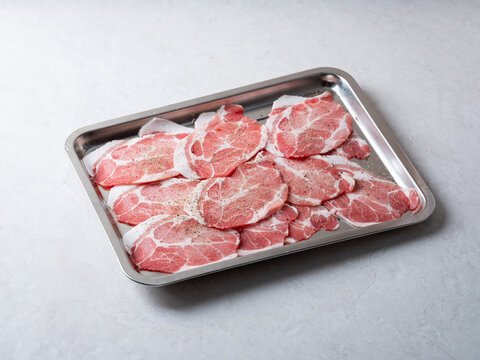 Fresh raw sliced pork neck or pork collar meat arranged in a stainless steel tray