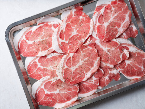 Fresh raw sliced pork neck or pork collar meat arranged in a stainless steel tray