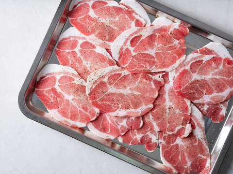 Fresh raw sliced pork neck or pork collar meat arranged in a stainless steel tray