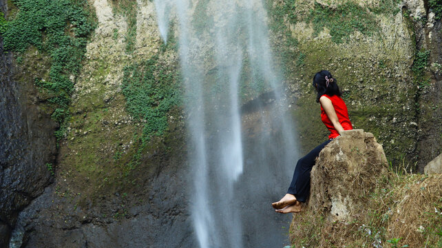 Woman in Red Sitting Near Cimahi Waterfall in West Java Indonesia Stock Photo