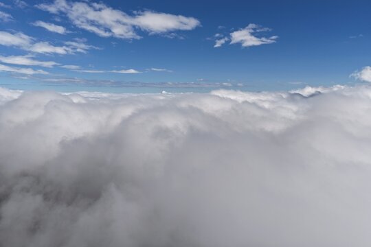 Aerial view of a thick layer of white clouds stretching to the horizon under a clear blue sky in Colorado, United States.
