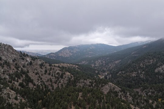Aerial view of Tram Hill featuring rugged rocky slopes, dense evergreen forests, and a cloudy sky over the mountainous landscape in Boulder County, Colorado, United States.