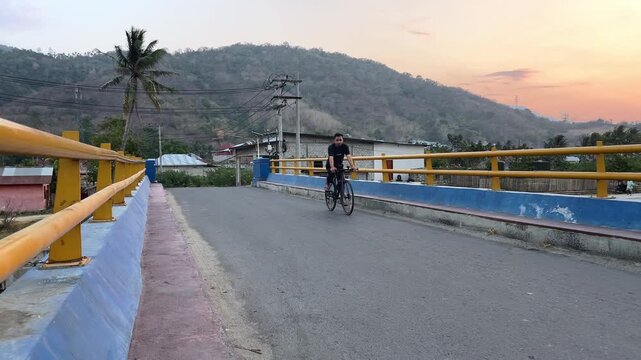 Man Cycling on a Bridge at Sunset