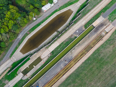 Aerial view of a vehicle testing facility featuring a water wading trough and paved tracks surrounded by grass and trees in the United Kingdom.