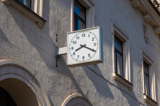 an outdoor clock on the building's facade, showing eight twenty