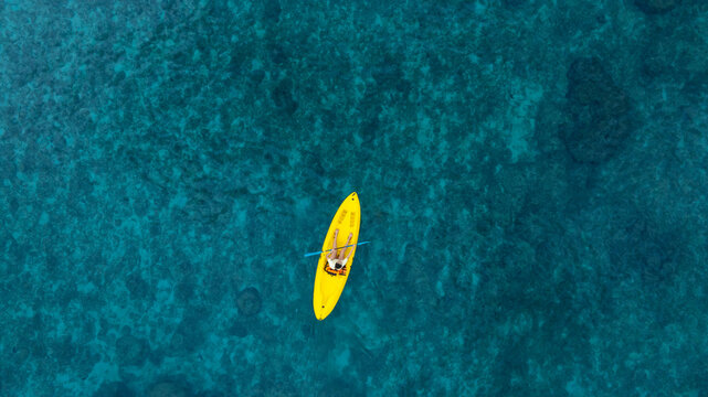 erial view of a woman and a young man kayaking on clear blue waters at Andaman Island. She does water sports activities