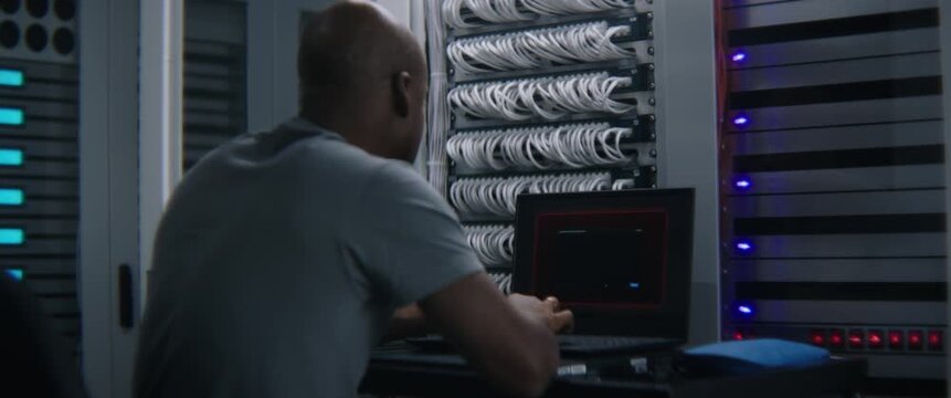 Male IT Engineer Monitoring Server Performance on Computer Screen as Critical Error Alert Appears. Enterprise IT Troubleshooting, System Failure Detection, Mission Critical Infrastructure Monitoring.