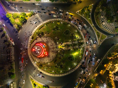 Aerial view of Tugu Muda roundabout in Semarang at night, featuring illuminated fountain, surrounding traffic, and city lights. Semarang, Central Java, Indonesia.